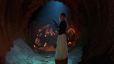 a woman is standing in a tunnel with candles