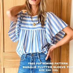 a woman wearing a blue and white striped top with her hands on her hips, standing in front of a wooden door