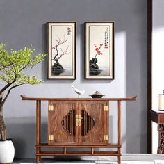 a living room with two framed pictures on the wall and a small table in front of it