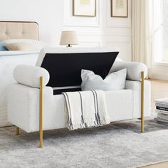 a living room with a white couch and some pillows on the floor next to a bed