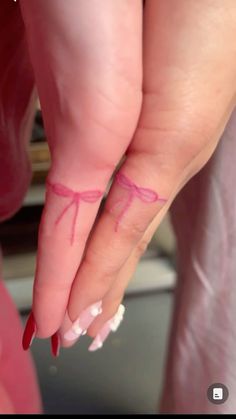 a woman's hand with pink nail polish and red bowknots on it