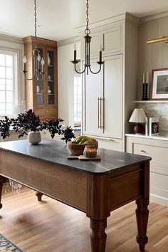 a large kitchen island in the middle of a room with white cabinets and wood floors