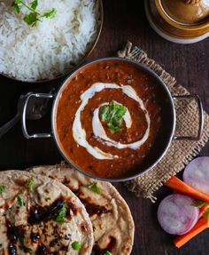 some food is sitting on a table next to rice and other foods that include carrots