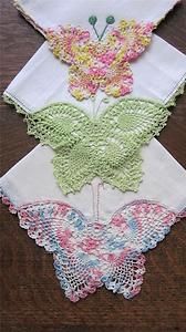 three pieces of cloth with butterfly appliques on them sitting on top of a wooden table