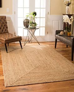 a living room with a chair, table and rug on the wooden floor next to an open door