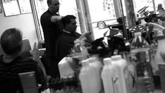 two men are sitting at a barber shop