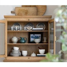 a wooden cabinet filled with dishes and cups