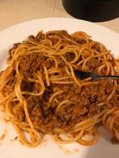 a white plate topped with spaghetti and meat