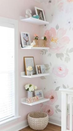 a baby's room decorated in pink and white with flowers on the wall, shelving