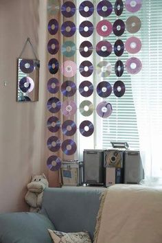 a living room filled with furniture and lots of vinyl records hanging from the wall above it