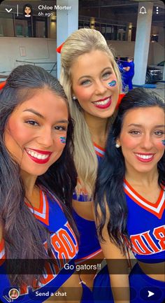 three cheerleaders posing for a photo in front of the camera with their faces painted on