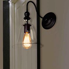 a light that is on the wall next to a mirror and lamp fixture with one bulb turned on