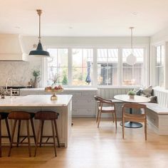 a kitchen with white cabinets and wooden stools next to an island in the middle