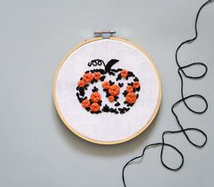 a cross - stitch pumpkin with black and orange flowers in the shape of a jack - o'- lantern