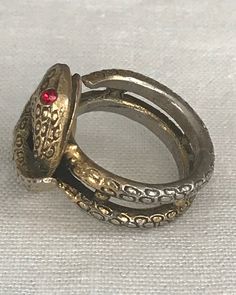 The two gold tone snakes with tiny red eyes are delicately wrapped around each other. The one snake has its body wrapped around the other one in the front of this ring and the second snake's body goes around and becomes the band of the ring and ends with the tip of its tale. This is a fun ring to wear. There are no markings on it. The double bands in the back of the ring are connected four tiny gold toned balls. This ring is in overall very good condition. Please see all photos and feel free to Adjustable Gold Metal Snake Ring, Antique Snake Ring As Gift, Adjustable Metal Snake Ring, Adjustable Gold Snake Ring Symbolic, Adjustable Gold Symbolic Snake Ring, Adjustable Snake-shaped Symbolic Rings, Adjustable Snake Symbolic Ring, Adjustable Symbolic Snake Ring, Symbolic Adjustable Snake Ring For Anniversary