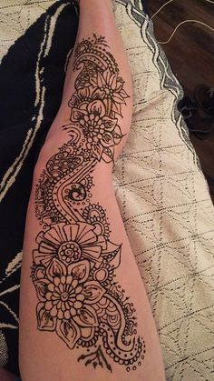 a woman's foot with henna tattoos on it, sitting on a bed