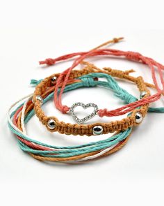 four different colored bracelets with silver beads and a heart on one end, two in the middle