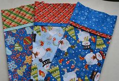 four pieces of fabric with snowmen and christmas decorations on them, all in different colors