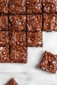 chocolate brownies cut into squares and placed on top of parchment paper with chocolate chips