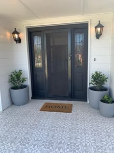 a front door with two planters and a welcome mat on the floor next to it