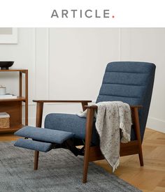 a blue recliner chair sitting on top of a wooden floor next to a book shelf