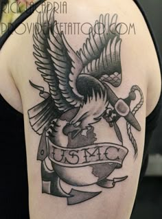 an eagle tattoo on the back of a woman's shoulder and arm with a ribbon around it