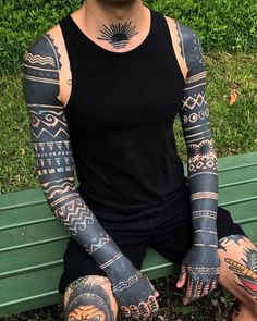 a man is sitting on a bench with tattoos on his arms and hands, all over his body