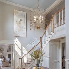 a living room filled with furniture and a chandelier hanging from the side of a staircase