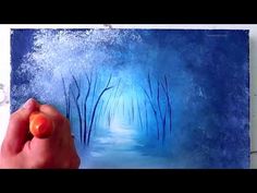 someone is painting a blue forest scene with an orange in the foreground and trees on the far side