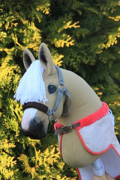 a stuffed horse is being held up by someone's hand in front of some trees