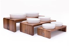 a wooden table topped with white bowls on top of each other and two tables below