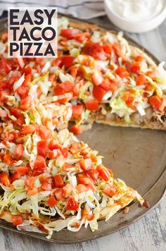 an easy taco pizza with shredded cheese, tomatoes and lettuce on top