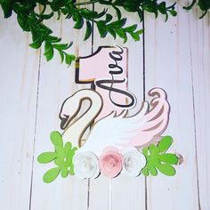 a cake topper with a flamingo on it and flowers in front of it