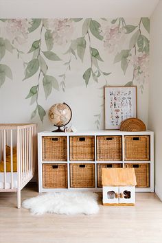 a baby's room with flowers painted on the wall and baskets in front of it