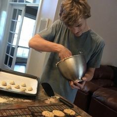 a man is cooking cookies on the grill with a pan and spatula in front of him