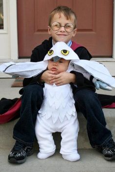 a young boy sitting on the ground with an eagle costume over his head and wings