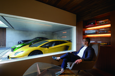 a man sitting in a chair with a yellow sports car on the wall behind him