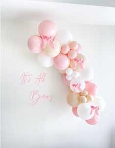 pink and white balloons are arranged in the shape of a letter m on a wall