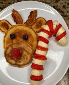 a plate topped with pancakes and fruit shaped like a dog face next to a banana split