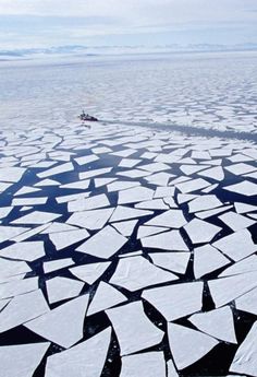 an aerial view of ice floes in the arctic with a plane flying over them