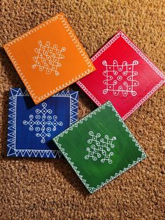 four different colored coasters with designs on them sitting on the floor next to each other