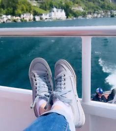 someone's feet hanging off the side of a boat with water in the background