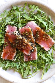 a white plate topped with meat and greens on top of a bed of lettuce