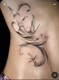 a woman's lower back tattoo with swirls and leaves on her side,