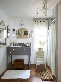 a bathroom with white walls and wood floors