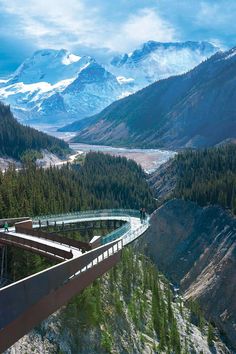 a bridge over a river with mountains in the background and people walking on one side