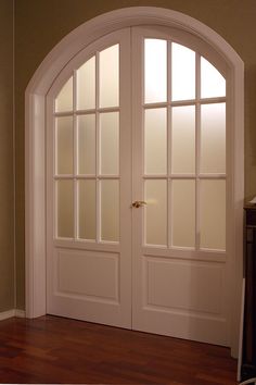 an arched white door with wood floors and hard wood flooring in front of it