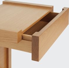 an open drawer on the side of a wooden table with drawers and handles in it