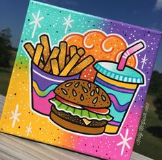 a painting of a hamburger and french fries on a wooden table with blue sky in the background