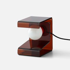 an orange and black table lamp with a white ball on the end, attached to a cord